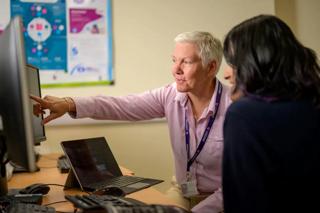 IT support specialist helping a staff member at her computer